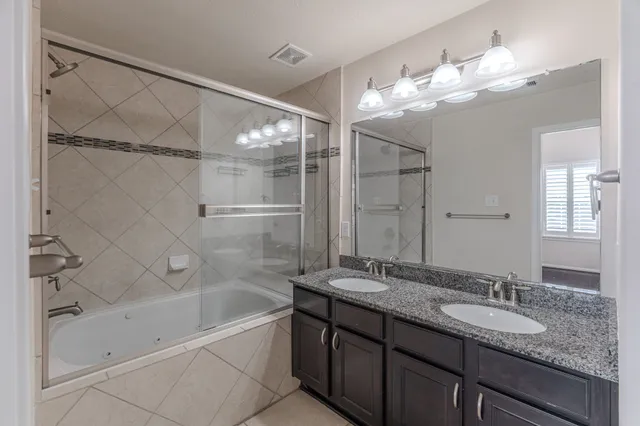 a bathroom with a granite countertop sink a large mirror and shower