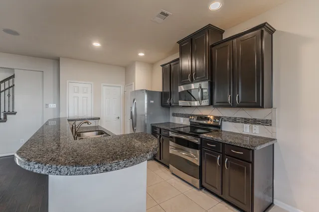 a kitchen with granite countertop stainless steel appliances and wooden cabinets