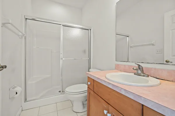 an empty room with chandelier fan and windows