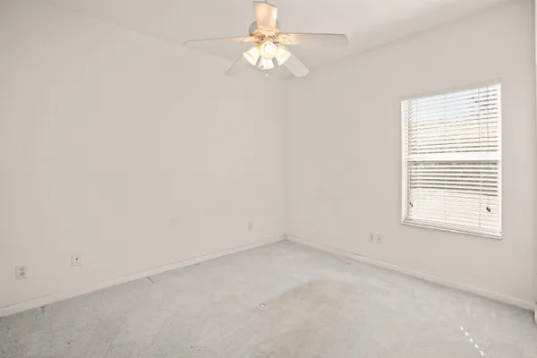 an empty room with windows and fan