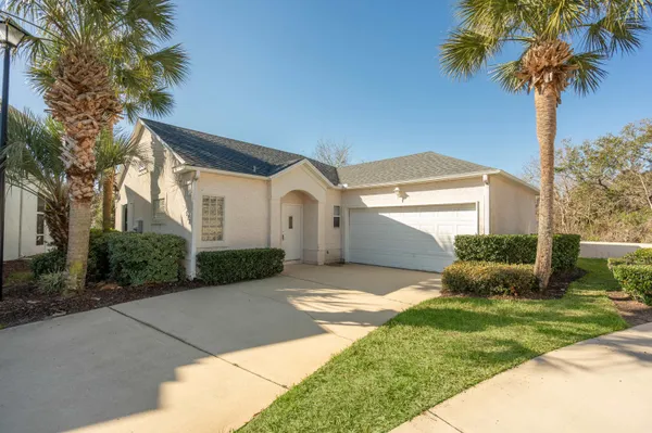 a view of a white house next to a yard with potted plants