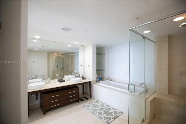 a bathroom with a double vanity sink mirror and bathtub
