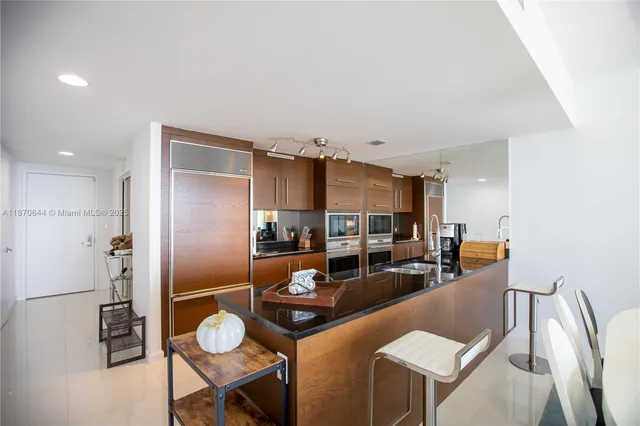 a kitchen with stainless steel appliances kitchen island granite countertop a table and chairs in it
