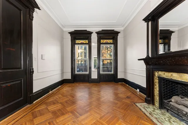 a view of an empty room with window and wooden floor
