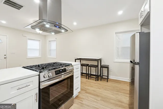 a kitchen with stainless steel appliances granite countertop a stove cabinets and wooden floor