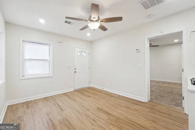 an empty room with wooden floor and windows