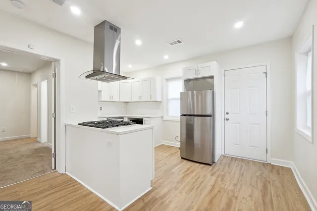 a kitchen with a stove a refrigerator and a wooden floor