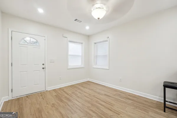 an empty room with wooden floor and windows