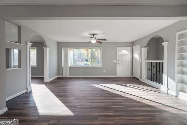 a view of an empty room with wooden floor and a window