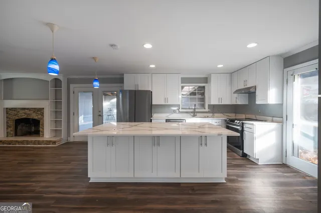 a kitchen with kitchen island granite countertop a stove and a refrigerator