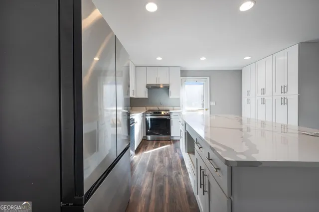 a large kitchen with a large counter top a sink stainless steel appliances and cabinets