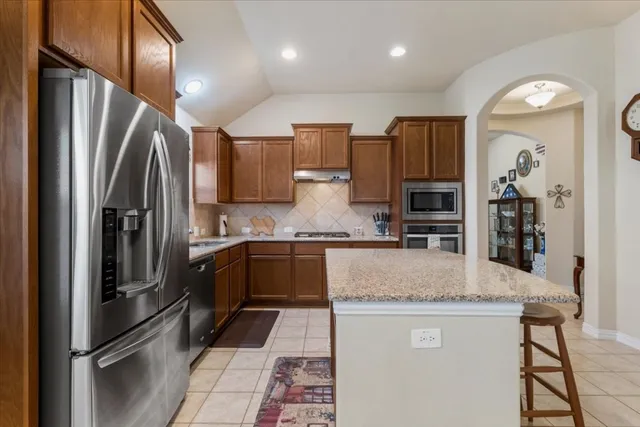 a kitchen with stainless steel appliances granite countertop a refrigerator a sink and a stove