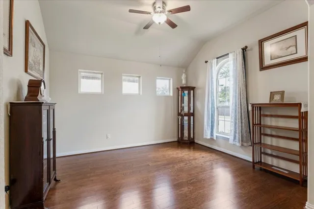 an empty room with wooden floor staircase and windows