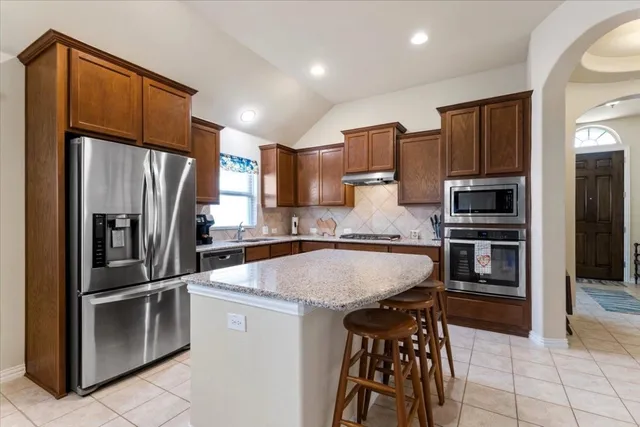 a kitchen with kitchen island a counter top space cabinets and stainless steel appliances