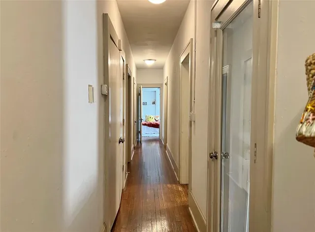 a view of a hallway with wooden floor and a bathroom