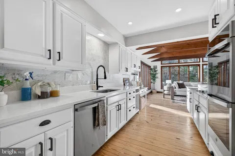 a kitchen with lots of counter top space a sink appliances and living room view