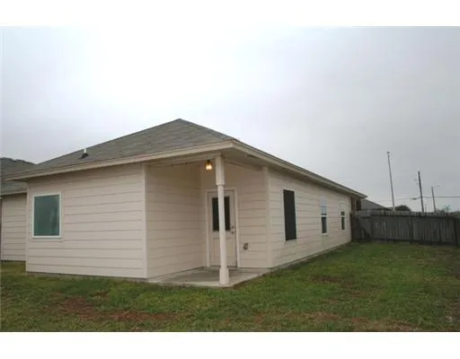 a backyard of a white house with wooden fence