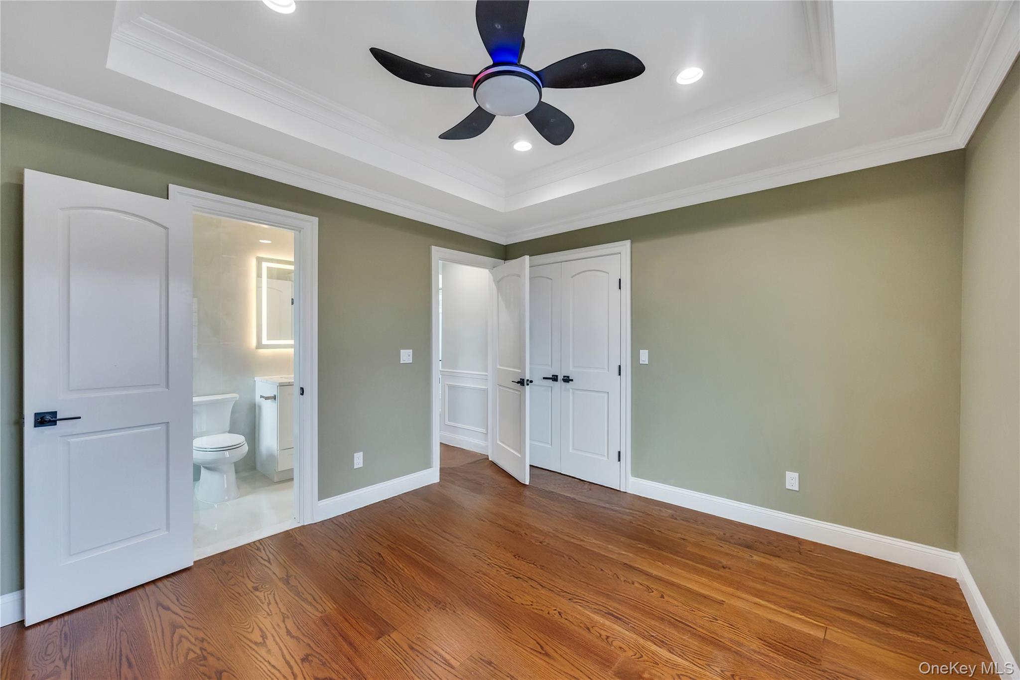 157 4th Street Hicksville, NY 11801 - Photo 14 of 20 Unfurnished bedroom with wood finished floors, connected bathroom, a raised ceiling, baseboards, and ornamental molding