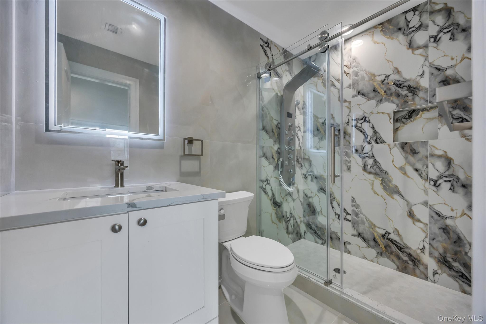 157 4th Street Hicksville, NY 11801 - Photo 15 of 20 Full bathroom featuring tile walls, toilet, vanity, and a marble finish shower