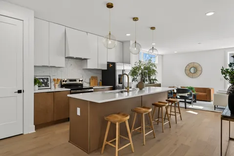 a kitchen with stainless steel appliances kitchen island granite countertop a stove a sink a dining table and chairs with wooden floor