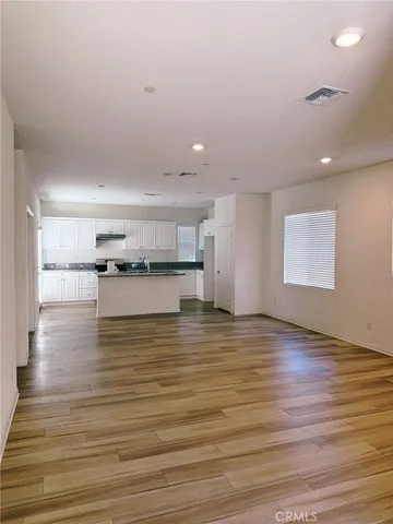 a view of kitchen and empty room with wooden floor