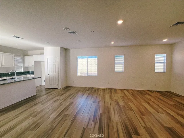 a kitchen with stainless steel appliances granite countertop a stove a sink dishwasher a refrigerator and white cabinets with wooden floor