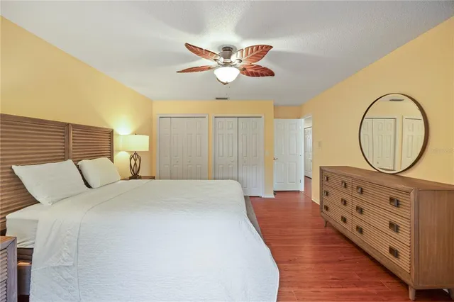 a bedroom with a bed a mirror on the dresser and a chandelier