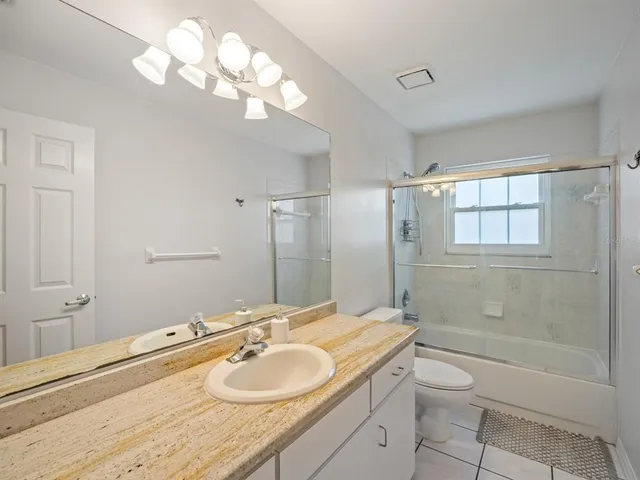 a bathroom with a granite countertop sink a toilet and shower