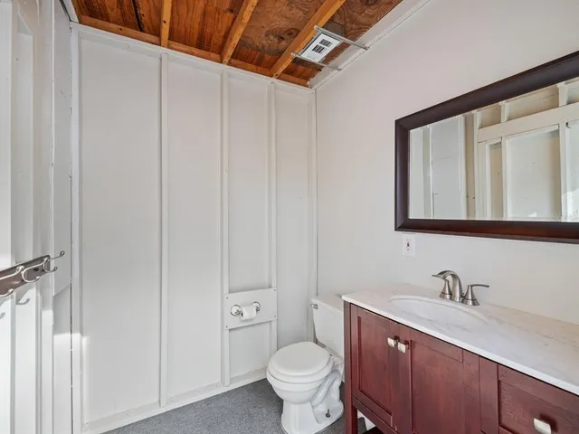 a bathroom with a granite countertop sink vanity mirror and toilet