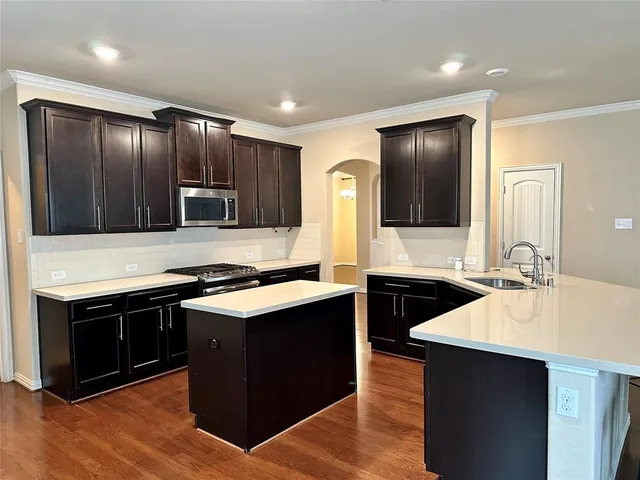 a kitchen with stainless steel appliances kitchen island granite countertop wooden cabinets and a stove top oven