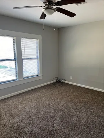an empty room with a ceiling fan and window