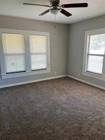 an empty room with windows and fan