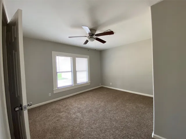 an empty room with windows and ceiling fan
