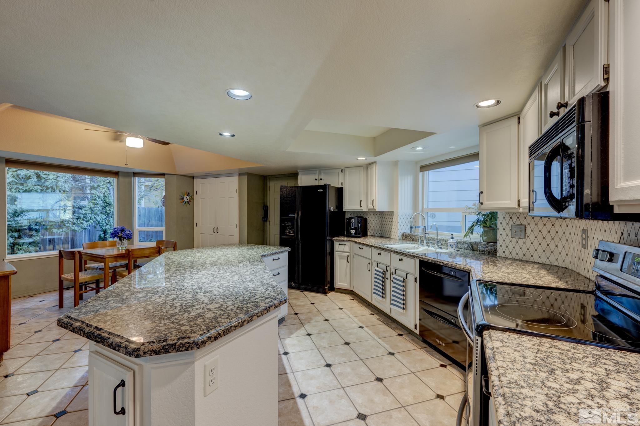 14095 Riata Circle Reno, NV 89521 - Photo 6 of 26 a kitchen with stainless steel appliances kitchen island granite countertop a table chairs and a refrigerator