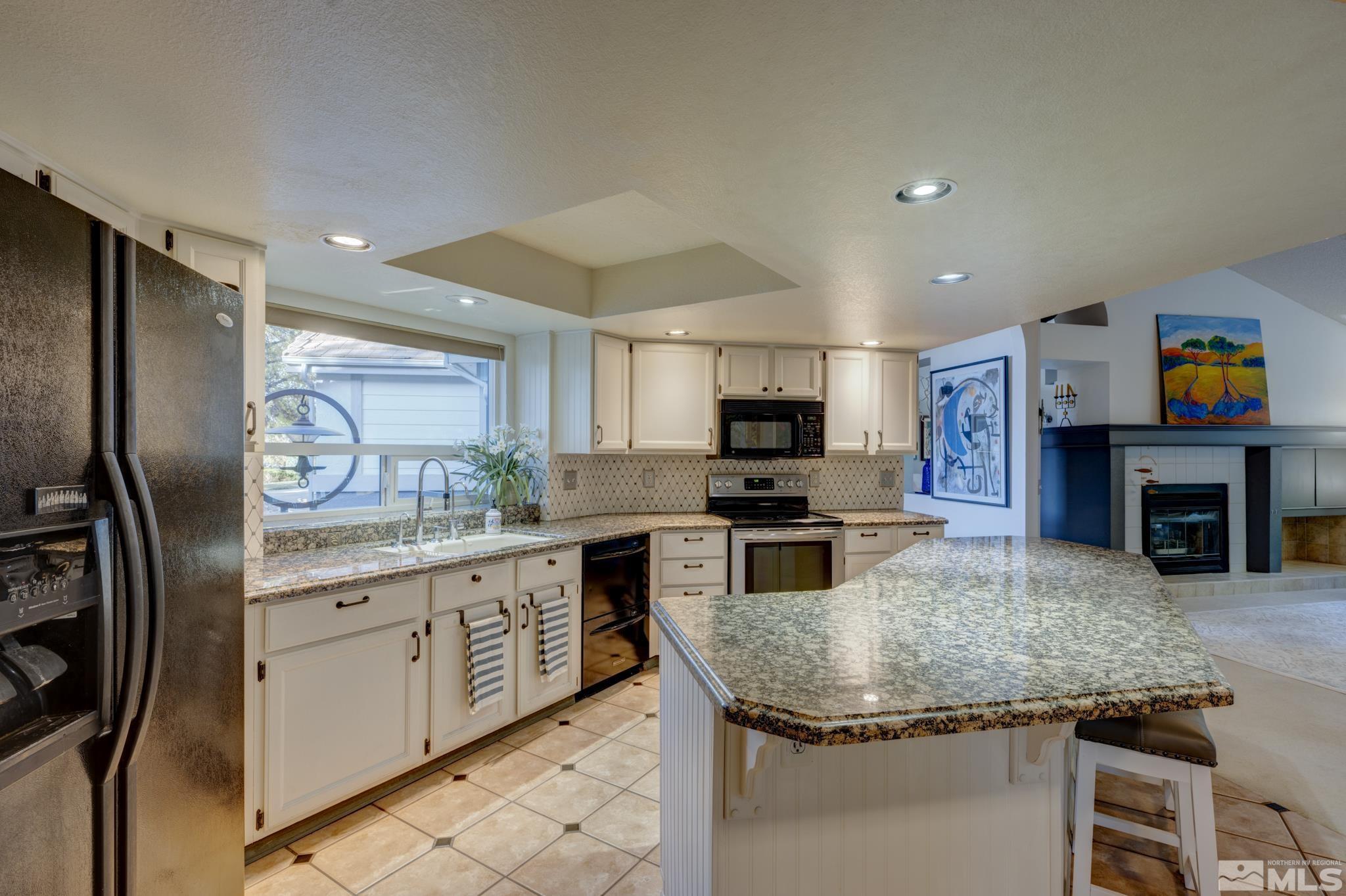 14095 Riata Circle Reno, NV 89521 - Photo 8 of 26 a kitchen with stainless steel appliances granite countertop a sink dishwasher stove and refrigerator