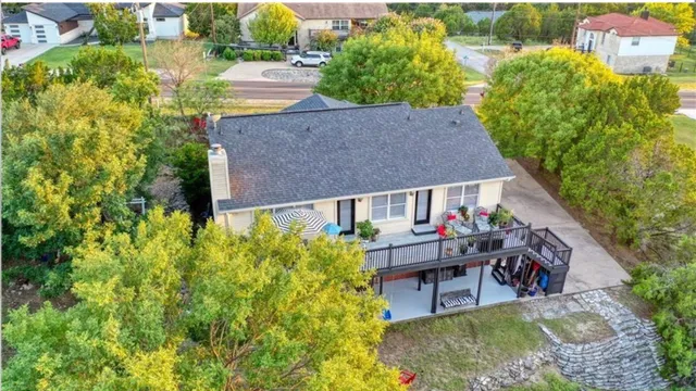 an aerial view of a house with swimming pool and large trees