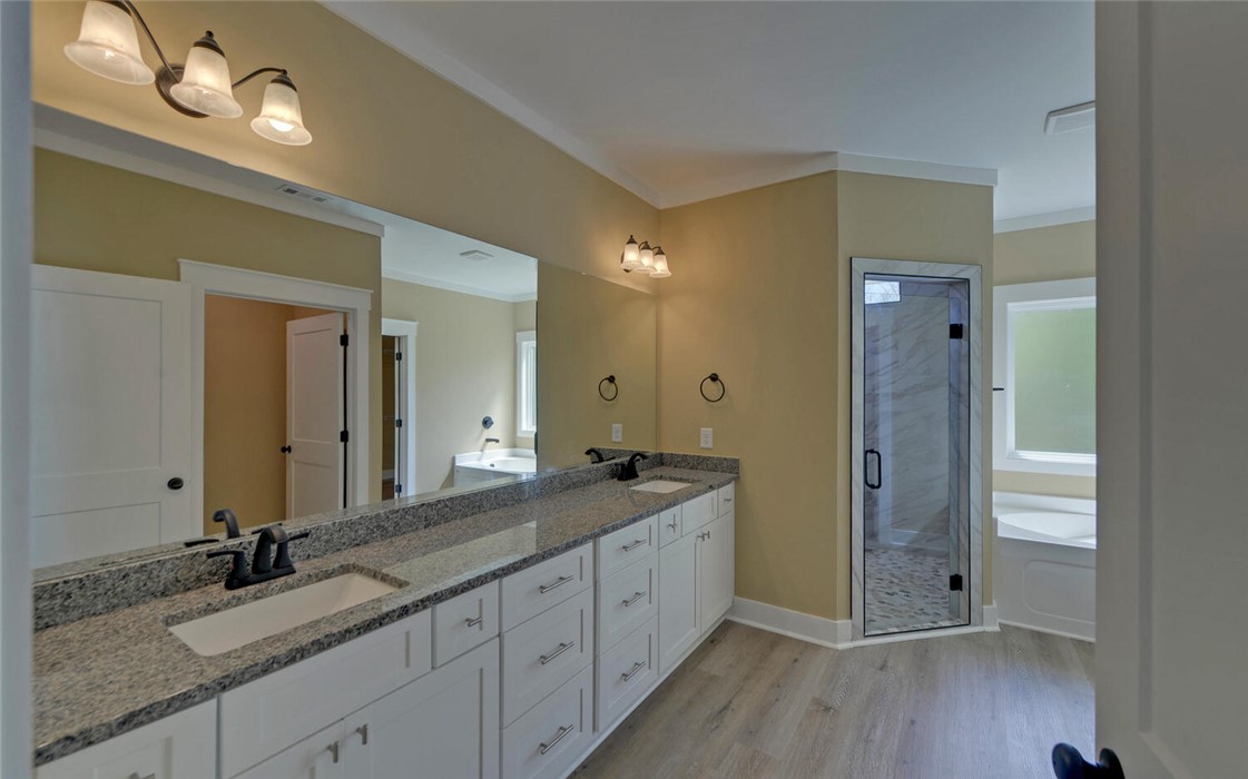 111 Topher Street Hartwell, GA 30643 - Photo 18 of 38 This primary bathroom features a double vanity, a glass-enclosed shower, and a soaking tub.