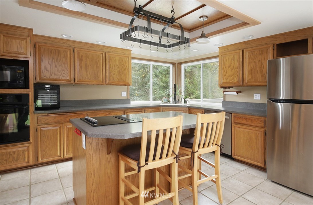 6793 Sills Road Clinton, WA 98236 - Photo 8 of 37 a kitchen with stainless steel appliances granite countertop a refrigerator a sink dishwasher a stove and a dining table with wooden floor