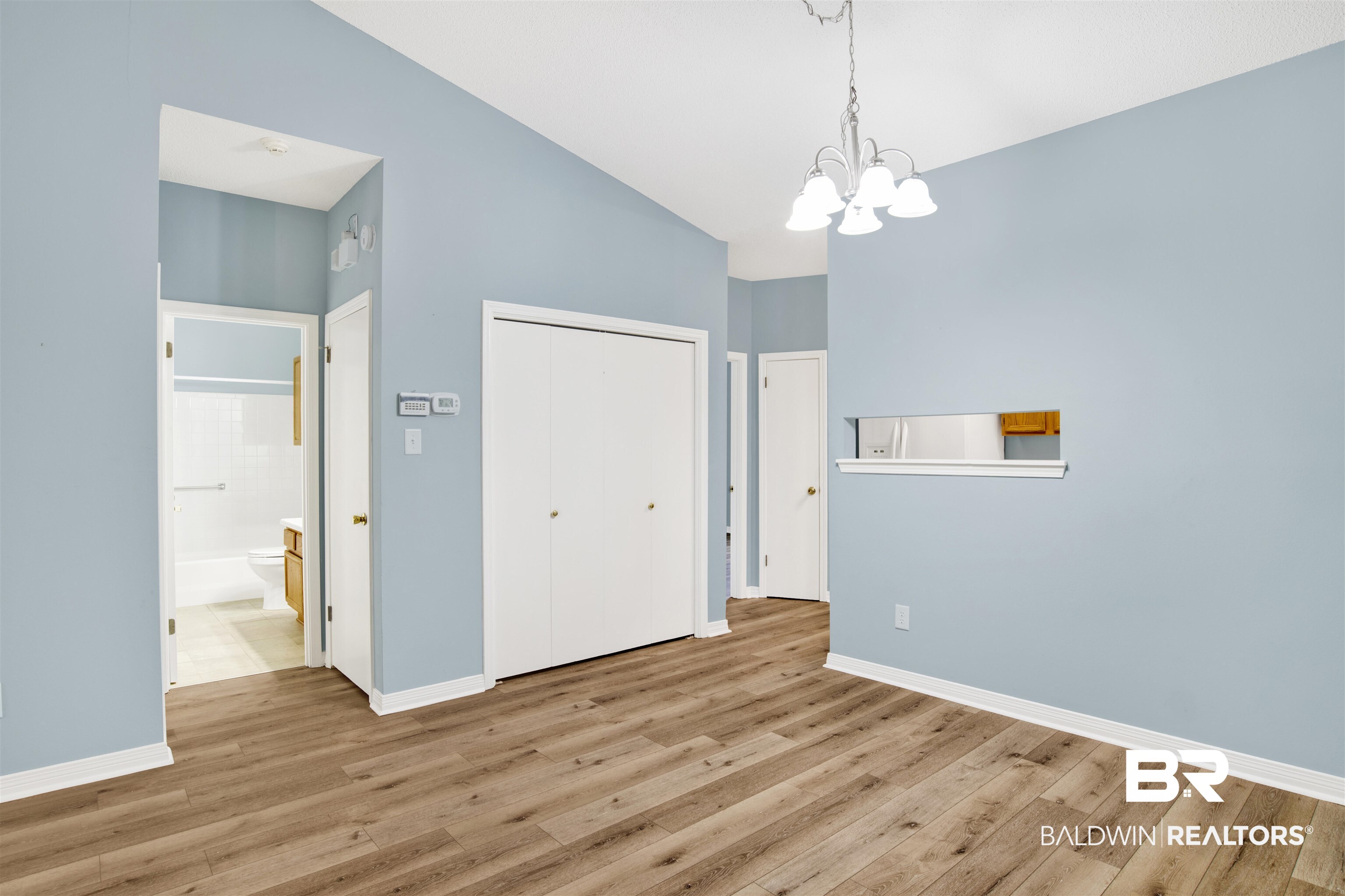1258 Sutton Court, Unit 4 Mobile, AL 36609 - Photo 6 of 19 Unfurnished dining area featuring baseboards, a notable chandelier, wood finished floors, and high vaulted ceiling