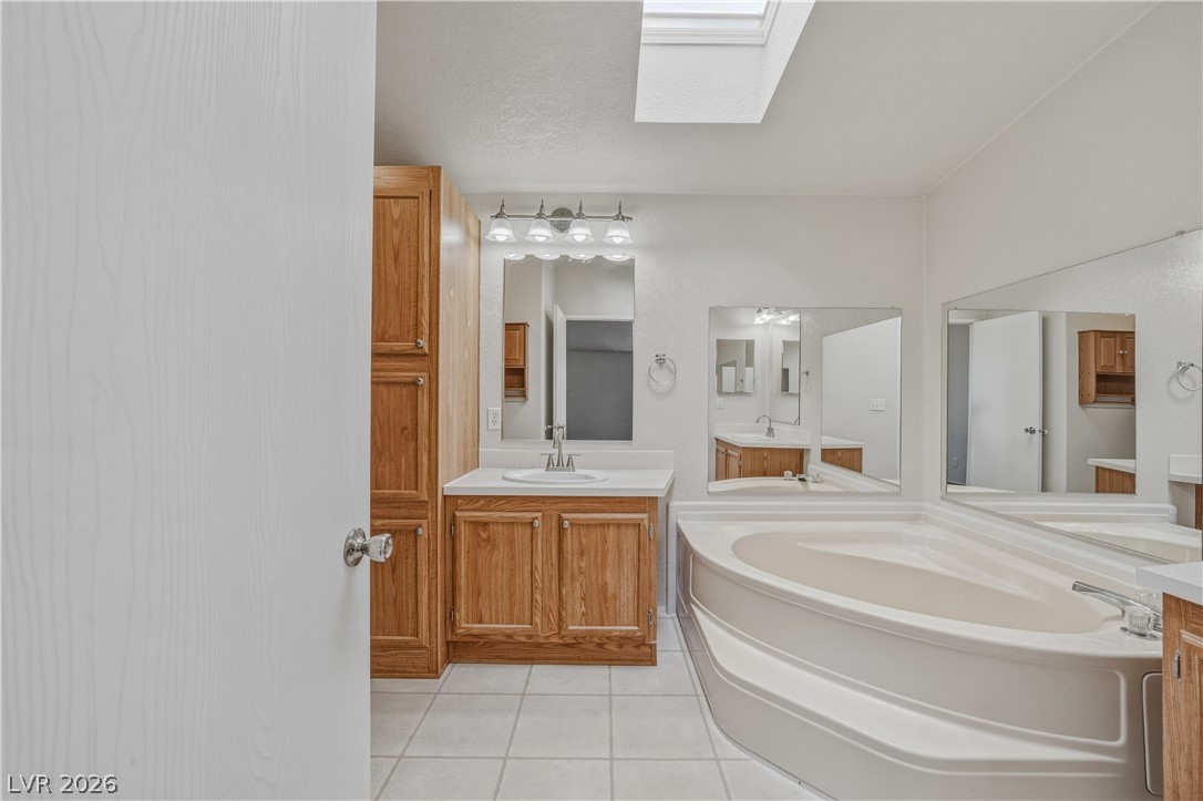 1890 West Dyer Road Pahrump, NV 89048 - Photo 31 of 40 Bright primary bathroom features a corner soaking tub and a vanity with ample storage.