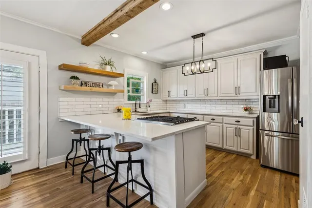 a kitchen with stainless steel appliances granite countertop a stove a sink dishwasher a refrigerator white cabinets and wooden floor