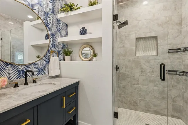 a bathroom with a granite countertop sink a mirror and shower