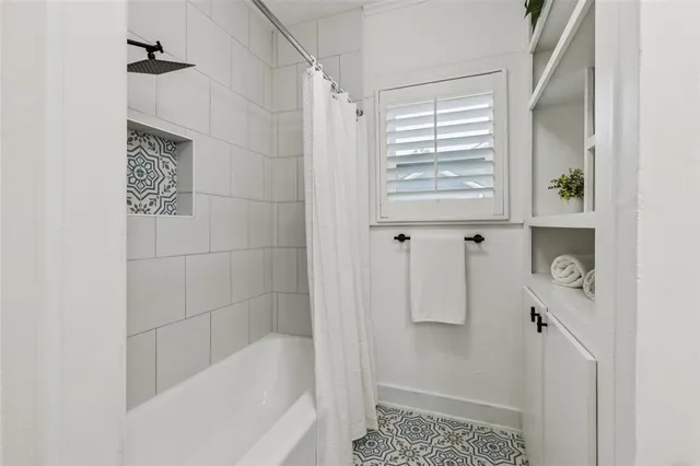 a bathroom with a bathtub a shower and a window