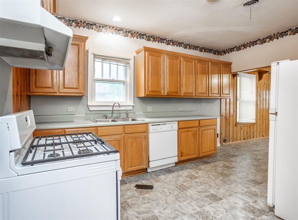 206 Ritchey Street Gainesville, TX 76240 - Photo 10 of 36 a kitchen with granite countertop a stove a sink and a refrigerator