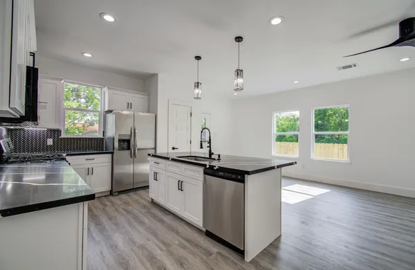 a kitchen with stainless steel appliances granite countertop a sink stove and wooden floor