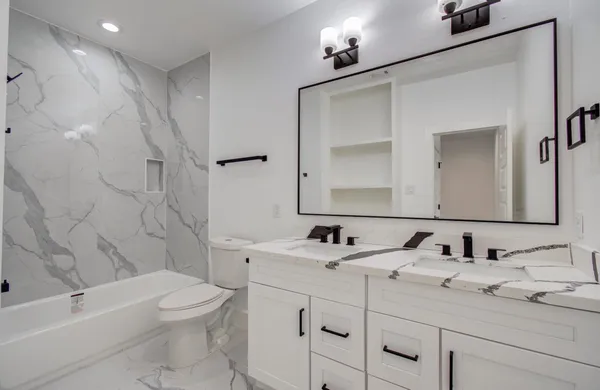 a bathroom with a toilet sink double vanity and bathtub