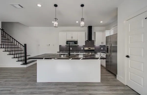 a kitchen with stainless steel appliances granite countertop a sink a stove a refrigerator and island with wooden floor