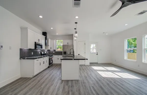 a kitchen with stainless steel appliances a stove top oven a sink dishwasher and a refrigerator