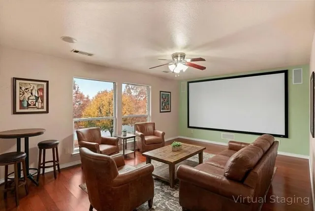 a living room with furniture a ceiling fan and a large window
