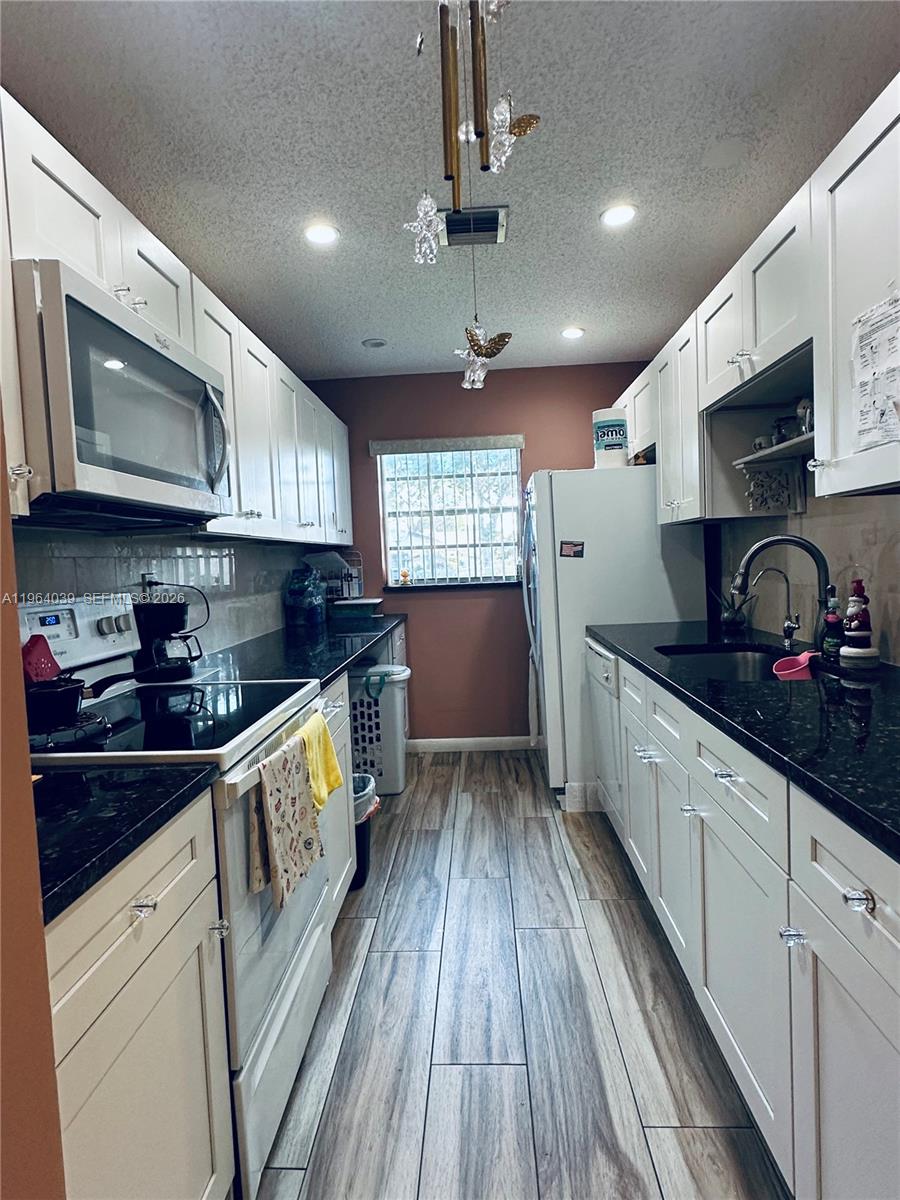 5260 Nesting Way, Unit B Delray Beach, FL 33484 - Photo 5 of 9 a kitchen with granite countertop wooden floors appliances a sink and a window